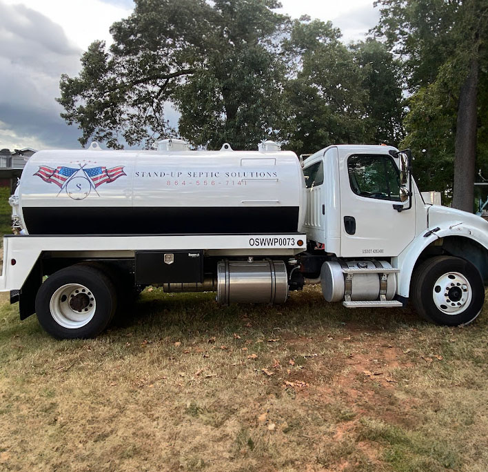 A white septic service truck labeled "Stand-Up Septic Solutions" is parked on grass, with trees in the background.