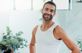 Portrait, smile and man in bathroom, skincare and confidence with routine, hygiene and cosmetics. Face, apartment and happy person with pride, grooming and treatment with dermatology, home and beauty